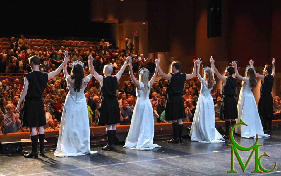 The cast of a play performed at the Chuck Mathena Center bowing after a performance and receiving applause from the audience.